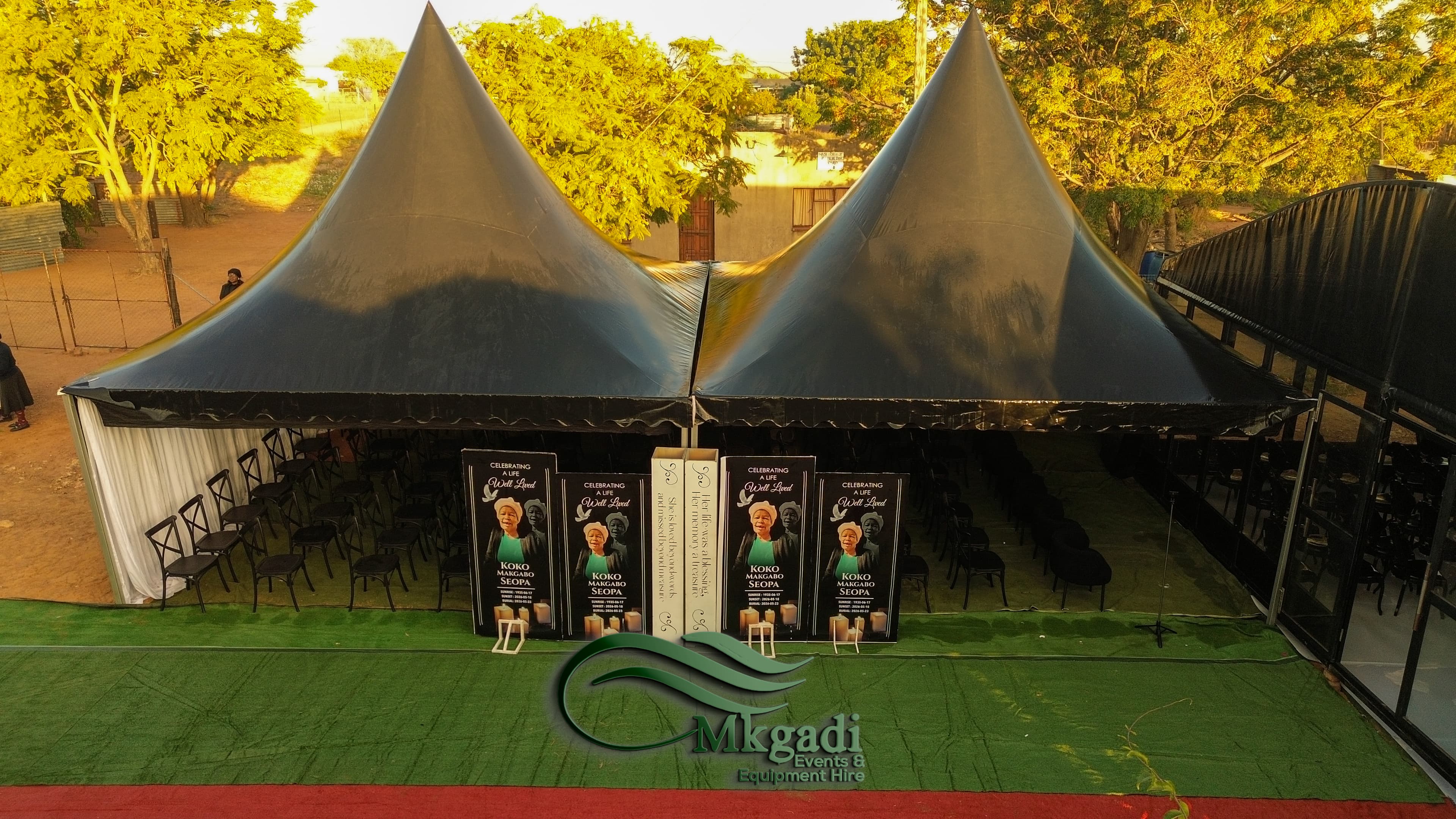 Aerial shot of outdoor event setup with pagoda tent and stretch marquee surrounded by trees in a residential area