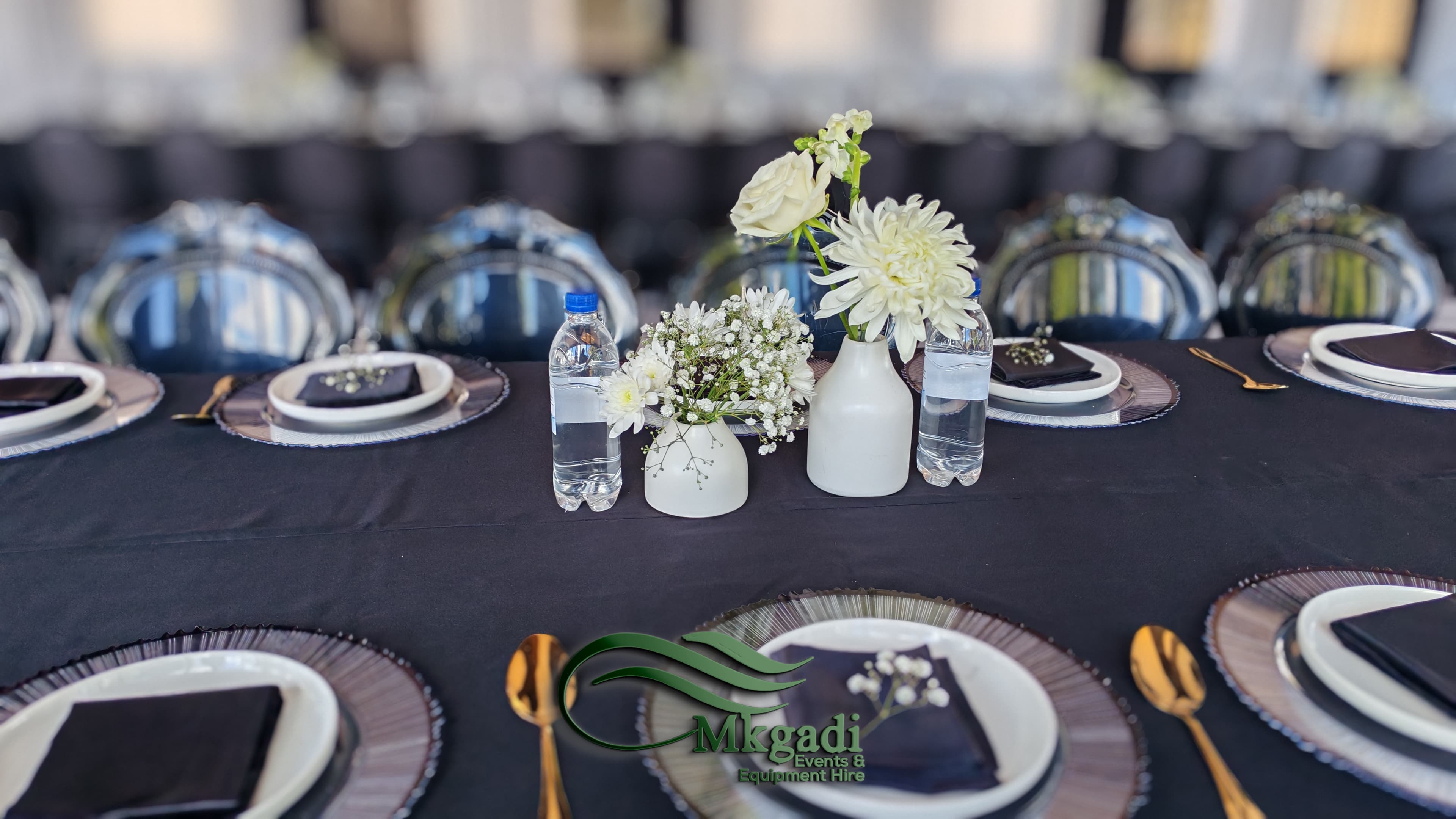 Elegant table setting with white linen, floral centrepiece and gold accents arranged for a formal reception