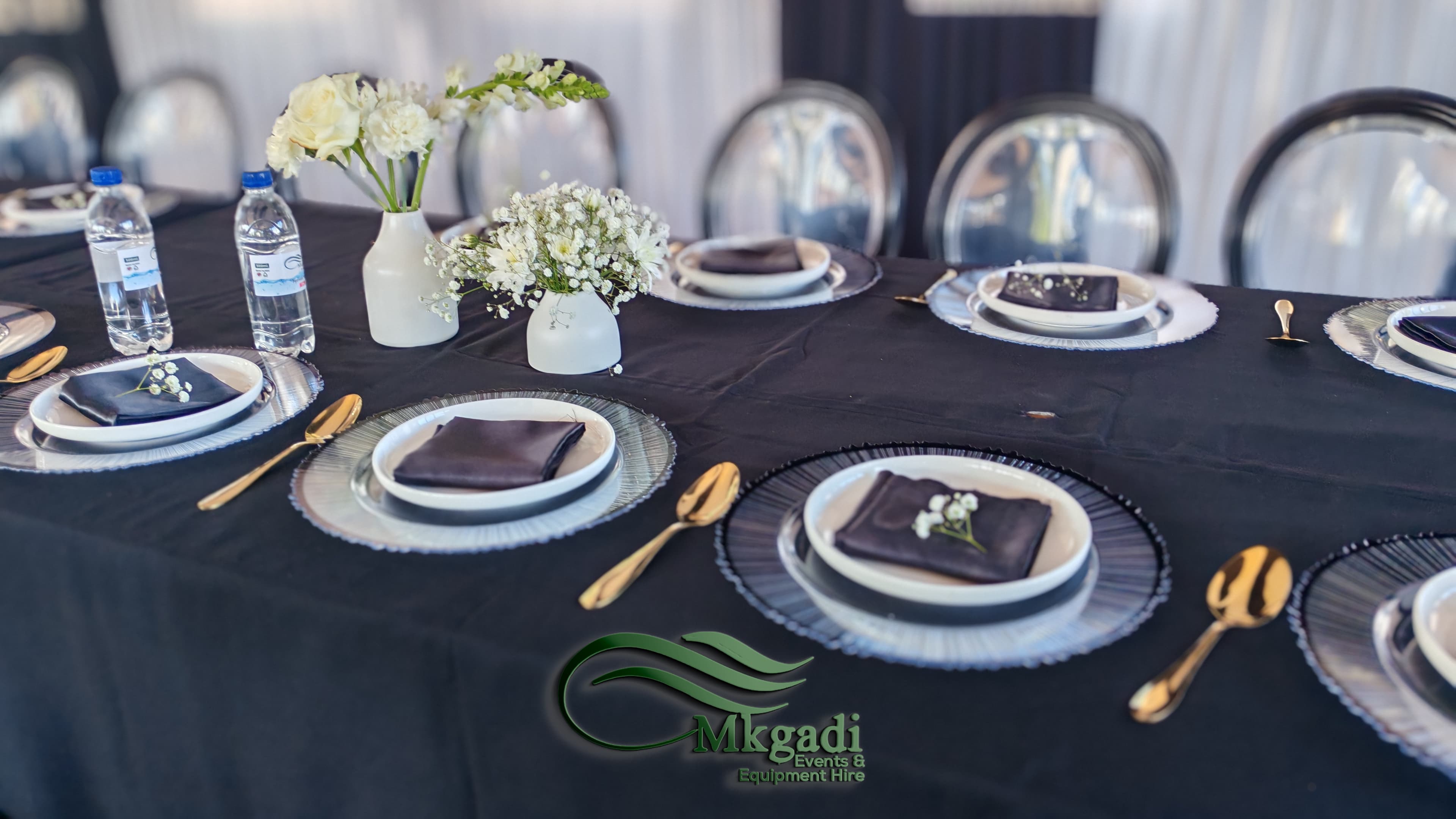 Wide shot of a fully decorated marquee tent interior with draped walls, round tables and elegant centrepieces for a large celebration