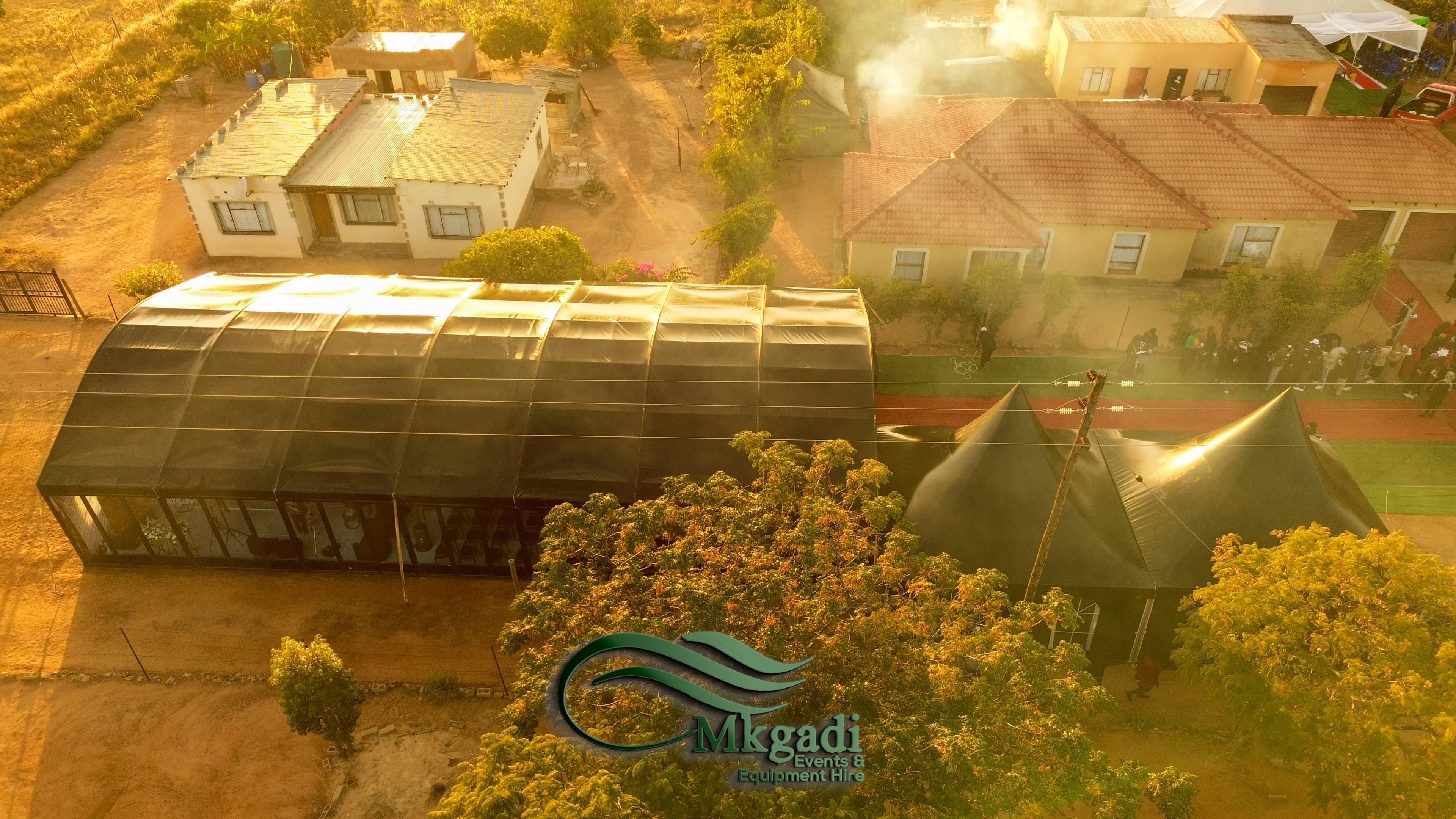 Aerial drone view of a large curved marquee tent set up in a South African neighbourhood at golden hour