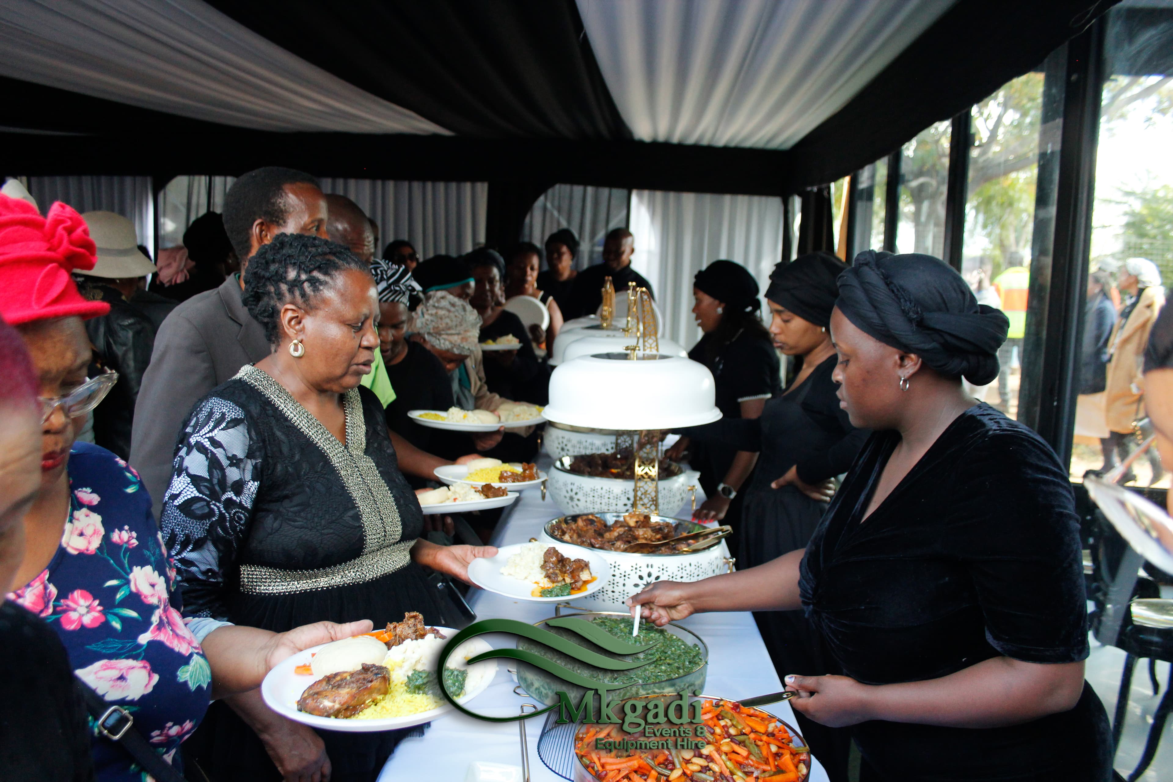 Mkgadi Events catering staff serving guests dressed in black at a funeral reception under a black marquee tent